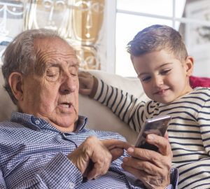 a grandfather and grandson looking at a smart phone.
